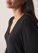 Close up of woman wearing black full length maxi dress with puffed 3/4 length sleeves
