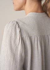 Woman wearing light blue and white check blouse 