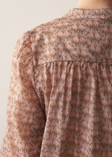 Woman wearing brown floral print top with dark blue jeans