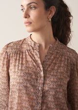 Woman wearing brown floral print top with dark blue jeans