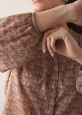 Woman wearing brown floral print top with dark blue jeans