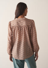 Woman wearing a brown floral blouse against a plain background