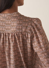 Woman wearing a brown floral blouse against a plain background
