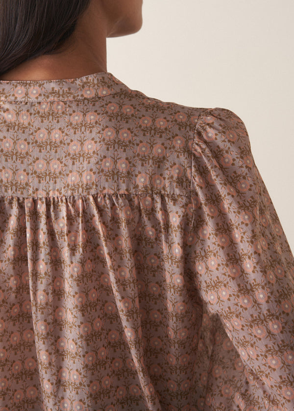 Woman wearing a brown floral blouse against a plain background