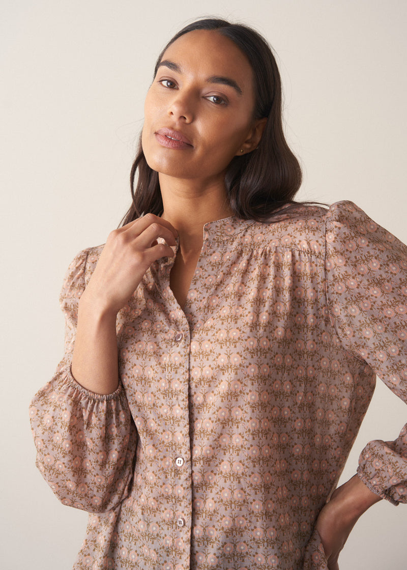 Woman wearing a brown floral blouse against a plain background