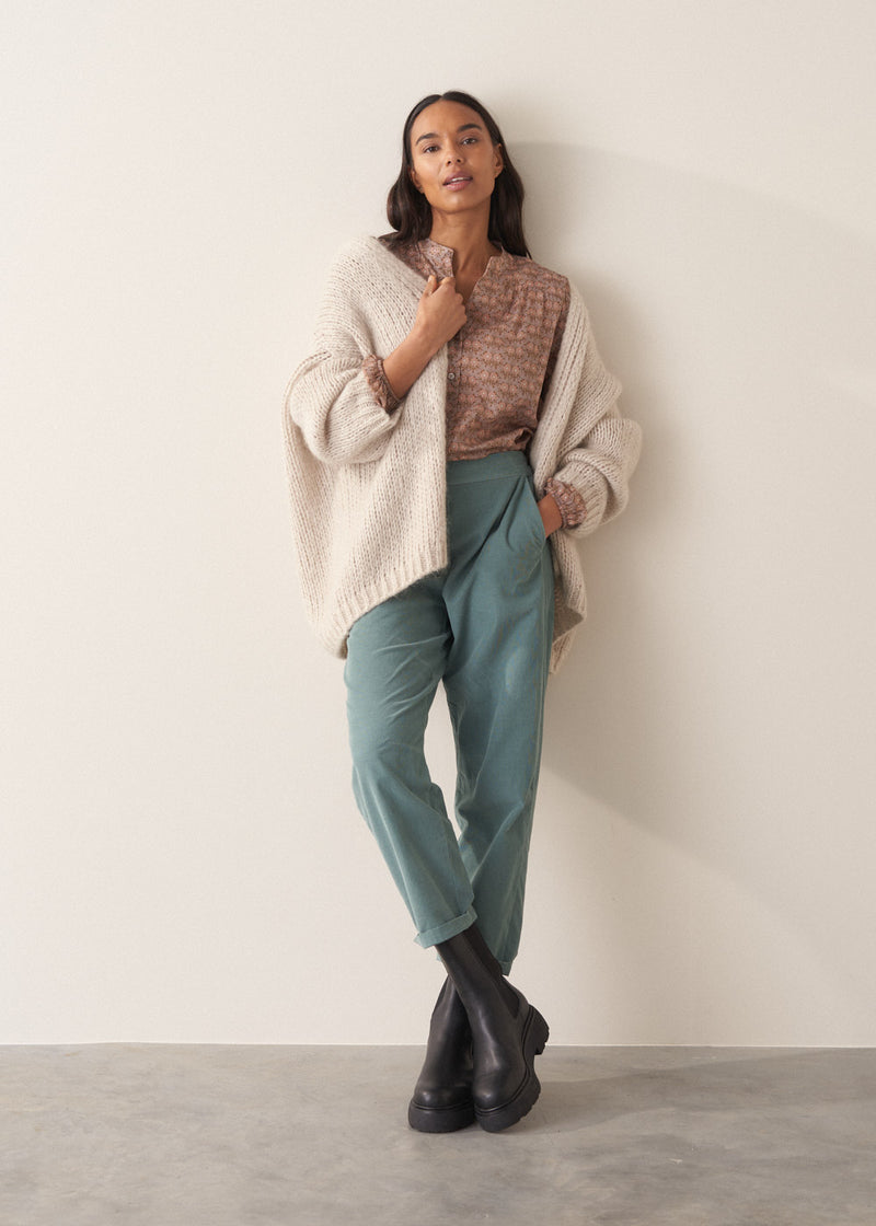Woman wearing a brown floral blouse against a plain background
