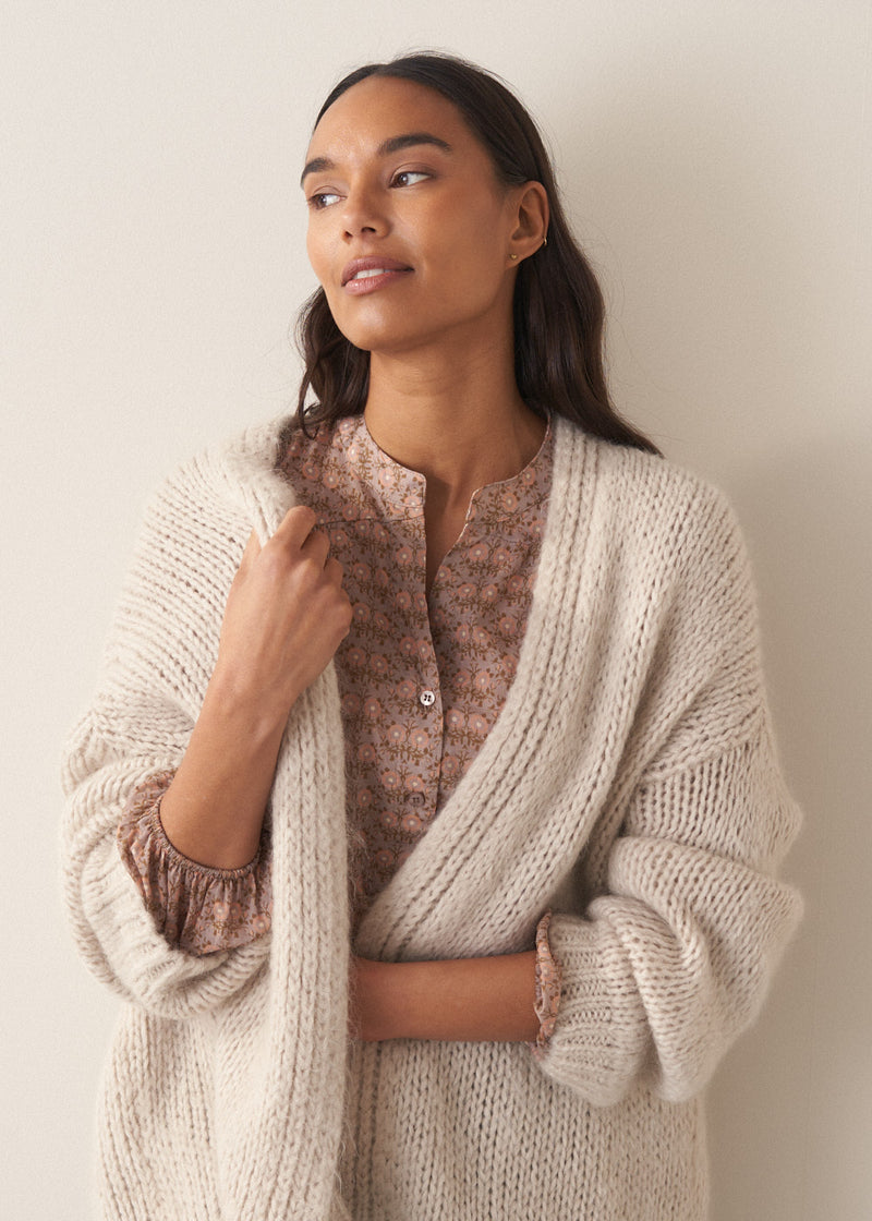 Woman wearing a brown floral blouse against a plain background
