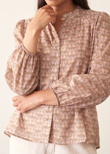 A woman wearing a long-sleeve button-up shirt with a small beige and brown floral pattern.