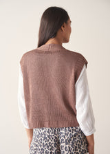 Woman wearing brown knitted waistcoat, a white cotton top and leopard print trousers