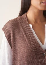 Woman wearing brown knitted waistcoat, a white cotton top and leopard print trousers