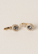 Pair of vintage style gold drop earrings with pearls surrounding a smokey grey crystal, on a beige background