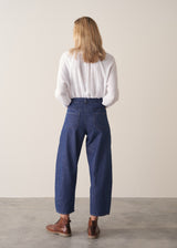 Woman wearing blue barrel leg jeans with a white cotton embroidered top.