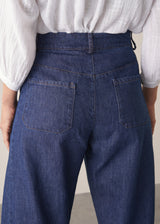 Woman wearing blue barrel leg jeans with a white cotton embroidered top.