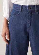 Woman wearing blue barrel leg jeans with a white cotton embroidered top.