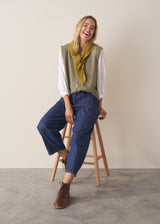 Woman wearing blue barrel leg jeans with a white cotton embroidered top.