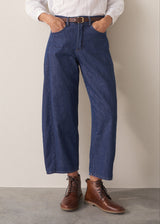 Woman wearing blue barrel leg jeans with a white cotton embroidered top.