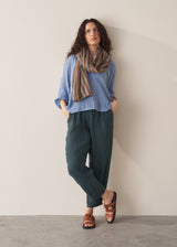 Woman wearing cornflower blue cotton blouse with dark teal linen trousers