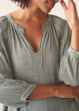 Woman wearing pale green cotton top with black linen trousers. 
