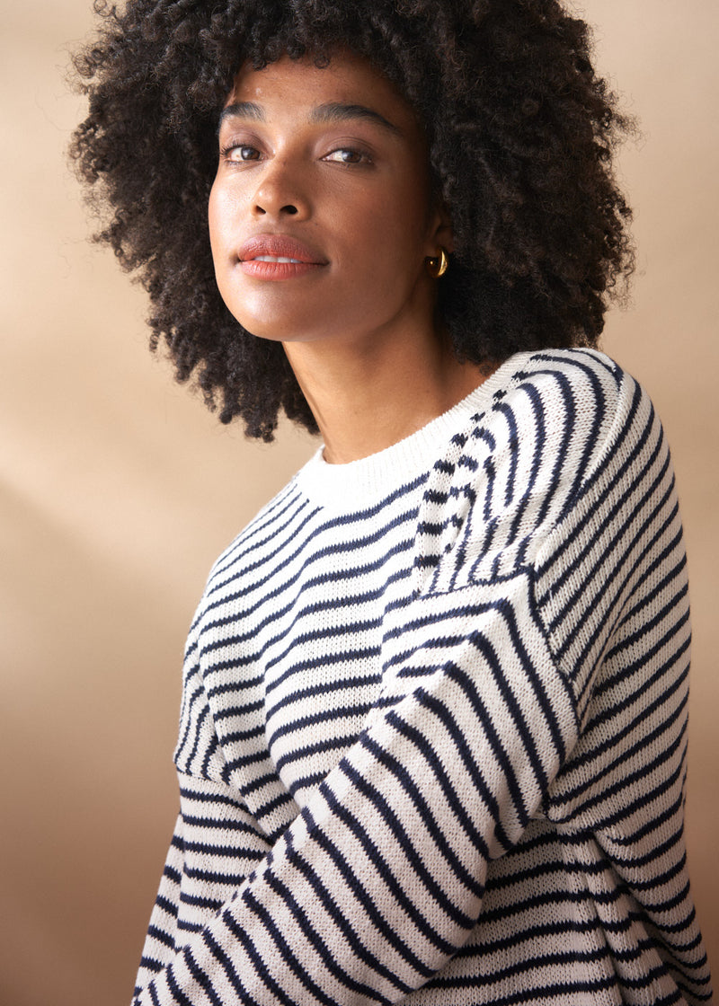 Close up of woman in a light knit stripe sweater with crew neck