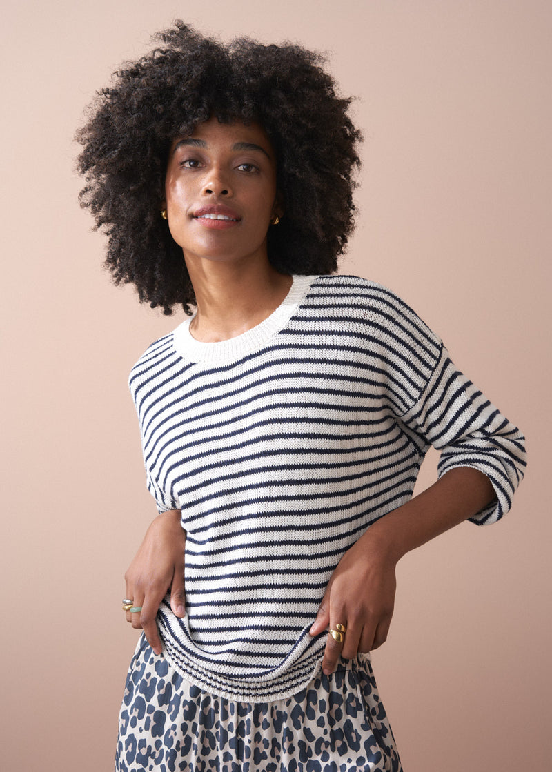 Close up of woman wearing striped knit jumper, with leopard dress.