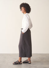 Woman wearing charcoal black stripe wide leg cropped trousers with a white broderie shirt.