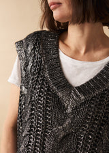 Woman wears a dark grey silver metallic cable knit vest with white top