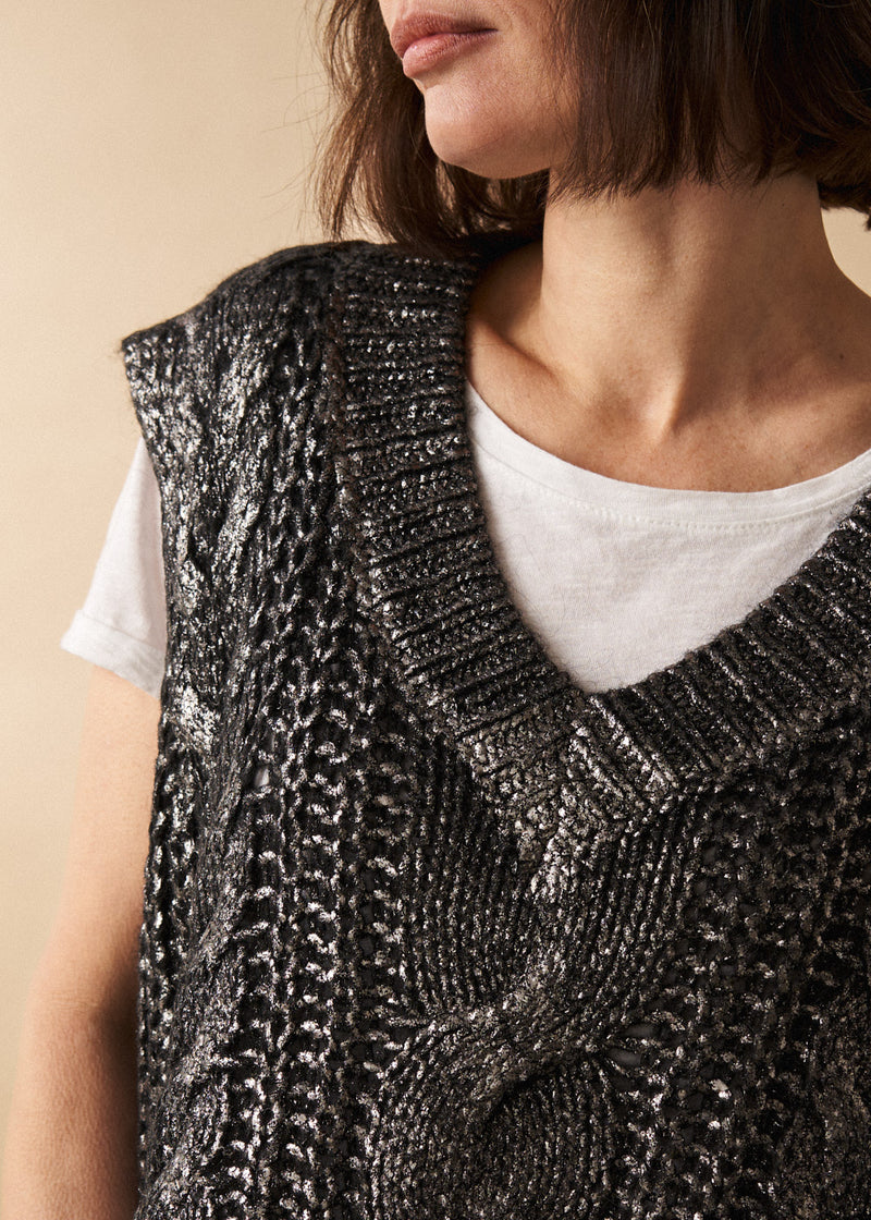 Woman wears a dark grey silver metallic cable knit vest with white top