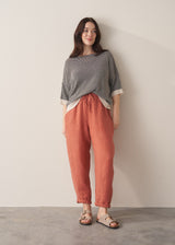 Woman wearing terracotta linen trousers with beige sandals and striped top