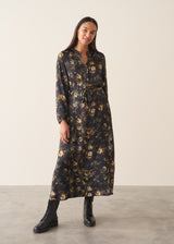 A woman wearing a long-sleeve, dark floral midi dress with a tie waist, set against a plain off-white studio background.