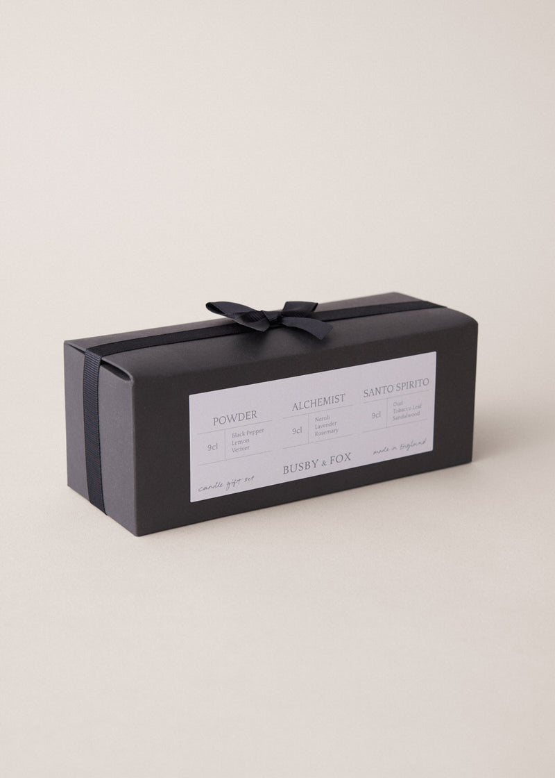 Set of three scented candles in a black bow tied gift box, on a beige background
