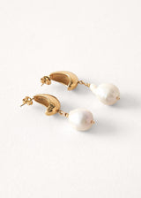 Side view of large gold pearl drop earrings on white background