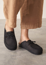 Pair of black moccasin slipper shoes on a grey concrete surface