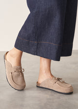 Pair of beige moccasin slipper shoes on a grey concrete surface