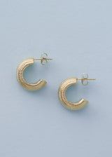 Textured gold hoop cuff earrings on a blue background