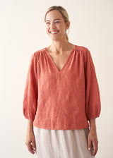 Woman wearing a pale terracotta cotton top with embroidery detail and a light linen skirt