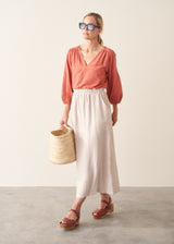 Woman wearing a pale terracotta cotton top with embroidery detail and a light linen skirt