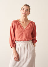 Woman wearing a pale terracotta cotton top with embroidery detail and a light linen skirt