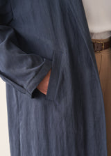 Woman wearing navy trench coat with light trousers and a white top
