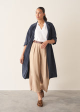 Woman wearing navy trench coat with light trousers and a white top