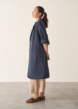 Woman wearing navy trench coat with light trousers and a white top
