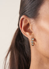 Women wearing crystal adorned open hoop earrings on beige background