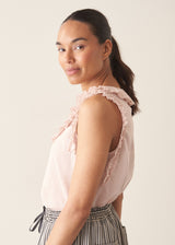 Woman wearing light pink chiffon blouse with ruffle collar and stripe wide leg trousers