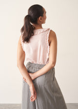 Woman wearing light pink chiffon blouse with ruffle collar and stripe wide leg trousers