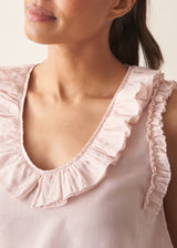 Woman wearing light pink chiffon blouse with ruffle collar and stripe wide leg trousers
