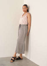 Woman wearing light pink chiffon blouse with ruffle collar and stripe wide leg trousers