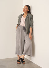 Woman wearing light pink chiffon blouse with ruffle collar and stripe wide leg trousers