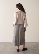 Woman wearing nude tie-front linen shirt with striped wide leg trousers.