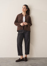 Woman wearing a brown faux suede jacket and dark jeans