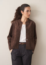 Woman wearing a brown faux suede jacket and dark jeans
