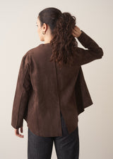 Woman wearing a brown faux suede jacket and dark jeans
